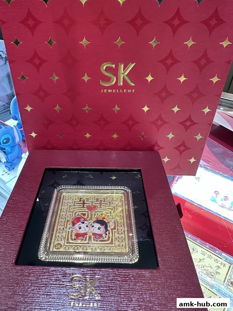SK Jewellery displays a gold ingot with a wedding couple design and branded packaging.