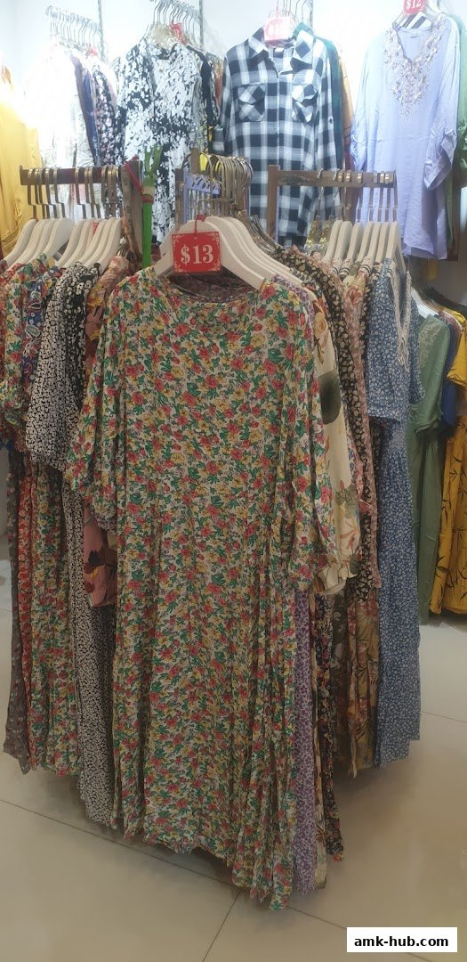 A display of floral and patterned dresses on hangers in a retail store.