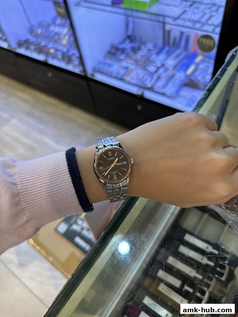 A person wearing a silver-banded watch with a dark face inside a retail store.