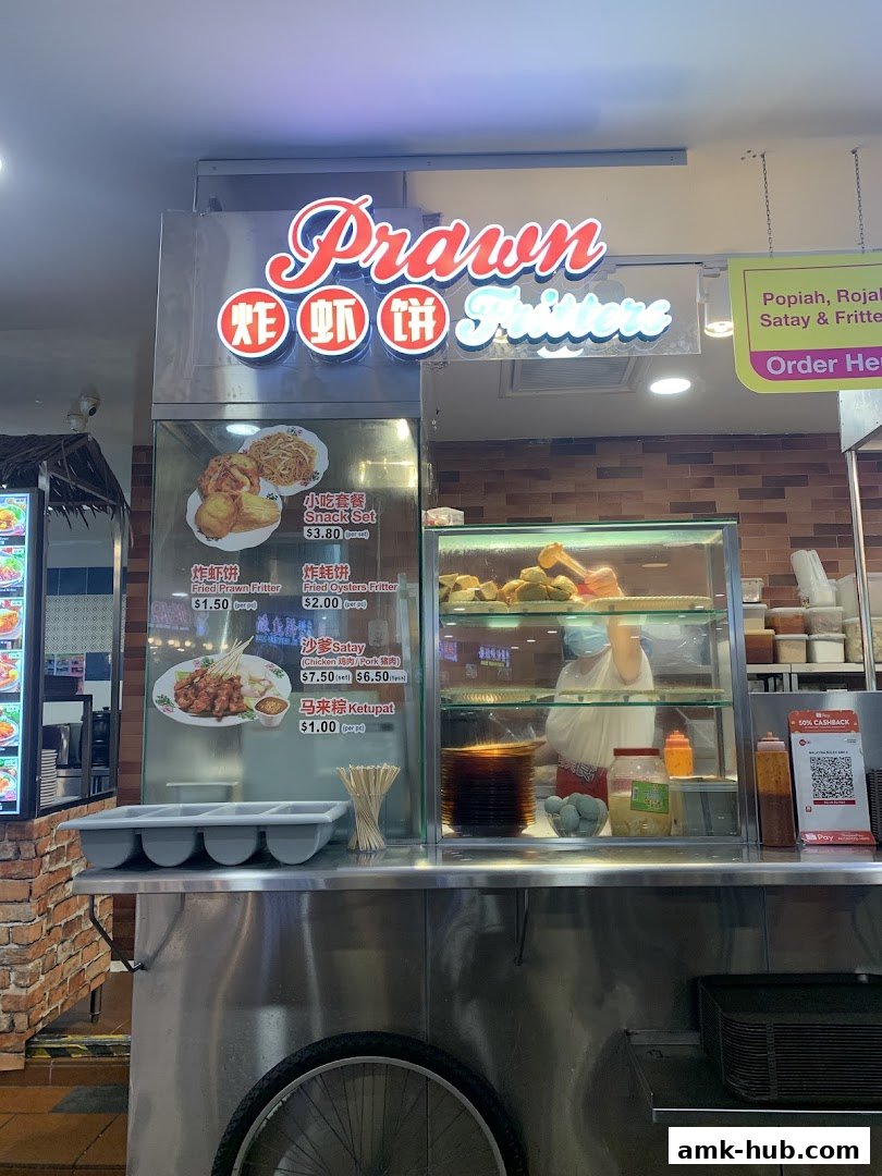 A food stall named Prawn Fritters selling various snacks and satay.