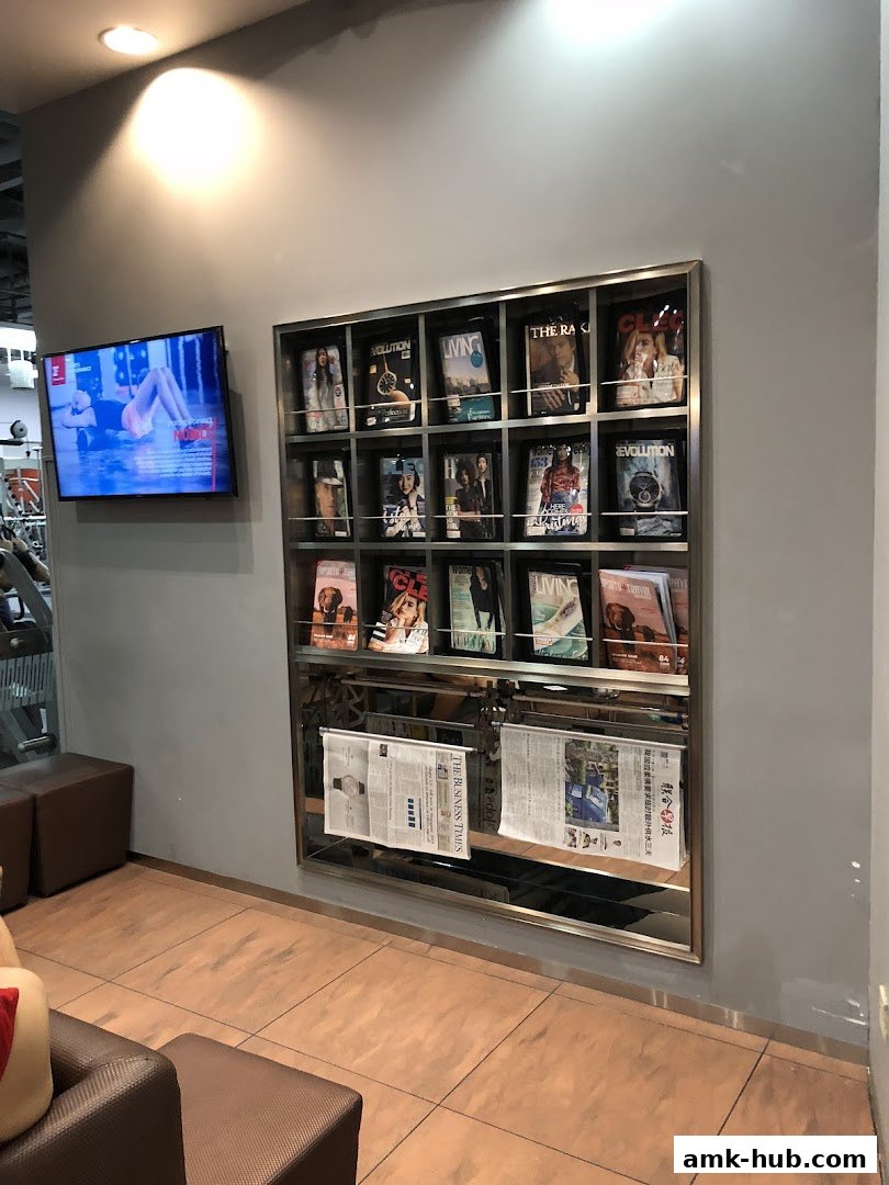 A wall with a TV screen and a rack displaying magazines and newspapers.