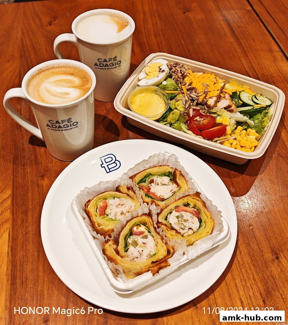 Two cups of coffee and a salad with chicken and a plate of four chicken wraps.