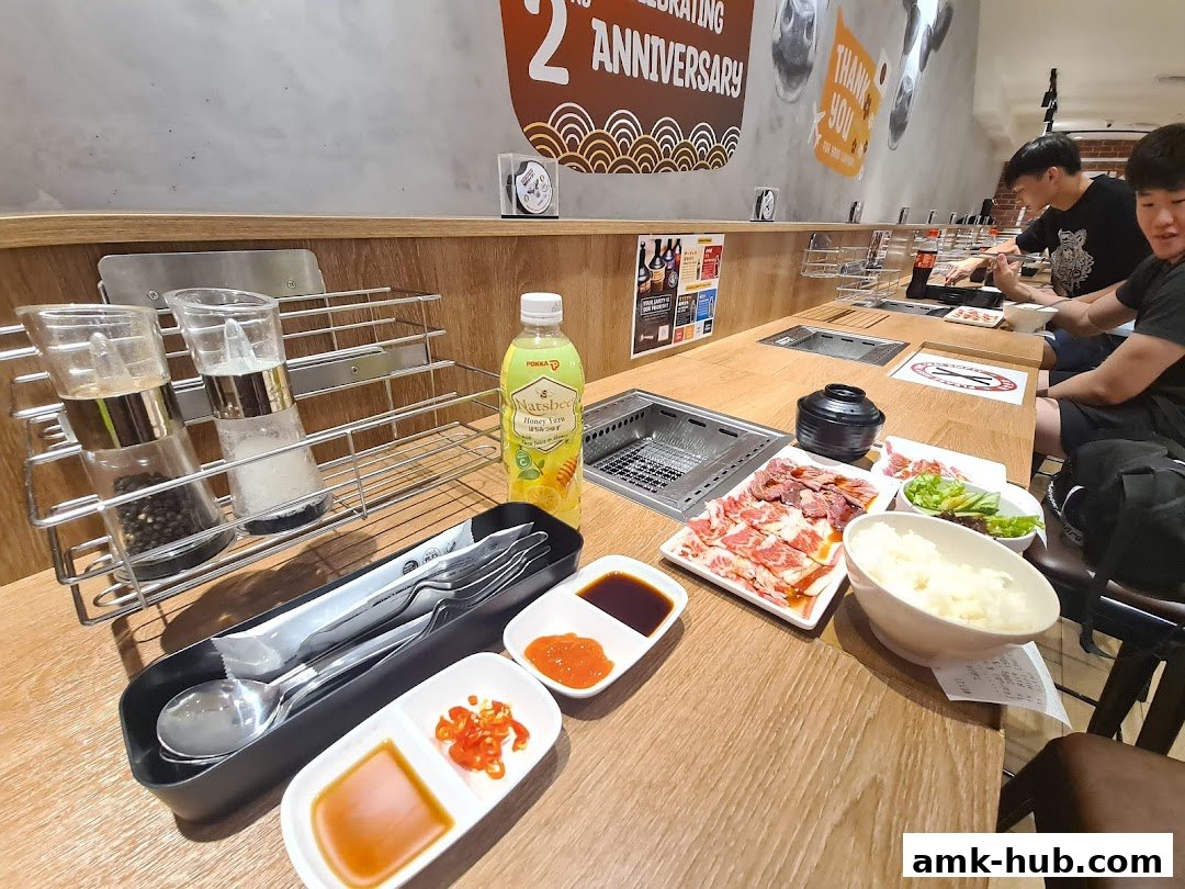Diners enjoy a Japanese BBQ meal with raw meat, rice, and condiments at Yakiniku Like.