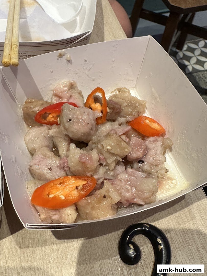 A close-up of dim sum in a white takeout container with chili slices.