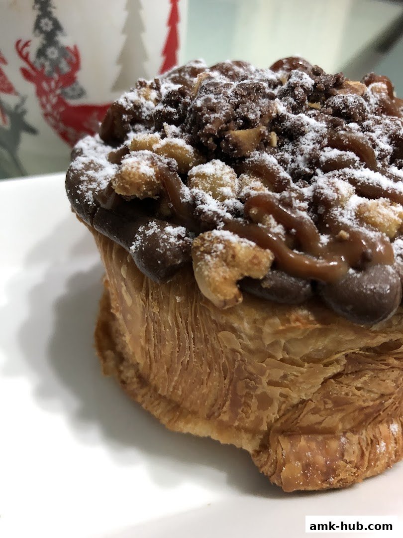 A close-up of a delicious pastry topped with chocolate, nuts, and powdered sugar.