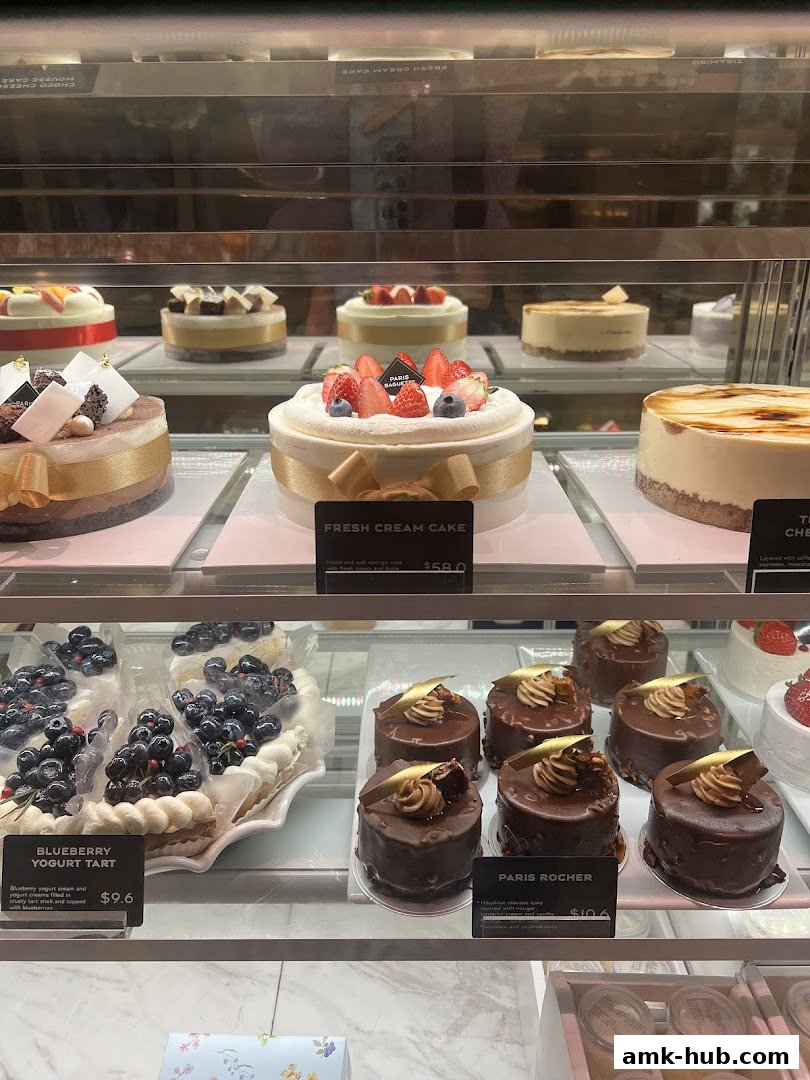 A display case filled with various cakes and tarts, including a fresh cream cake and blueberry yogurt tart.