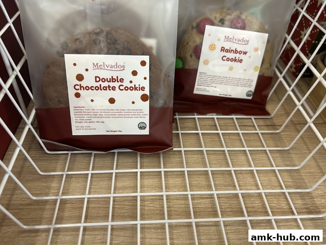 Packaged cookies, a double chocolate and a rainbow cookie, displayed in a white wire basket.
