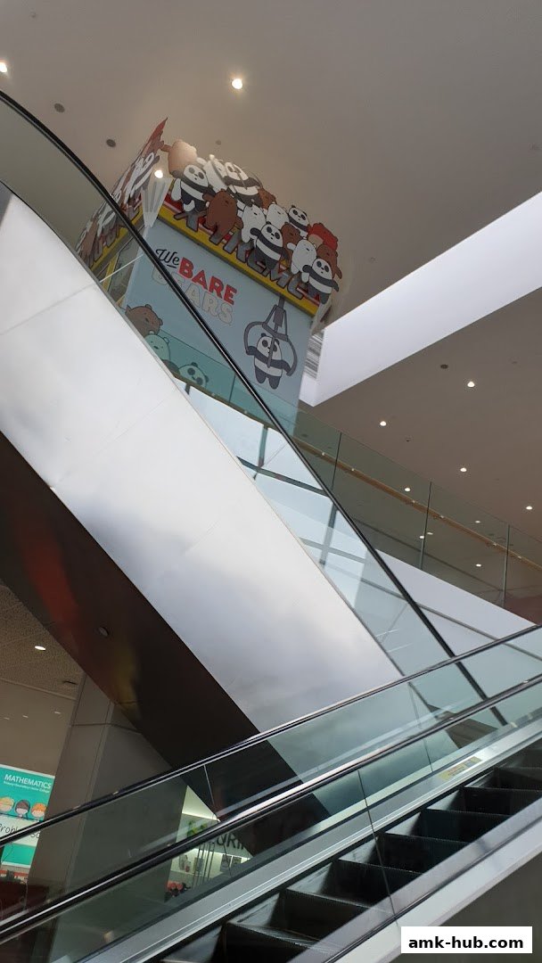 Escalators in a mall with a 'We Bare Bears' themed display above.
