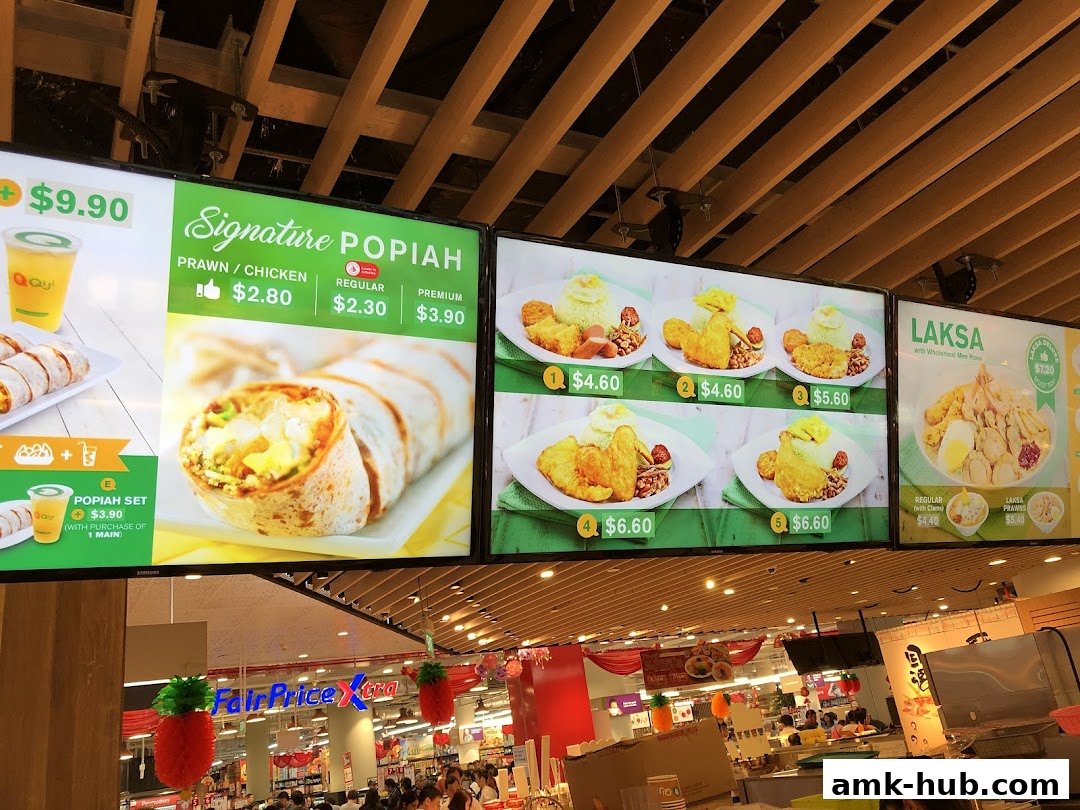 A digital menu board displaying various food items like Popiah and Laksa with prices.
