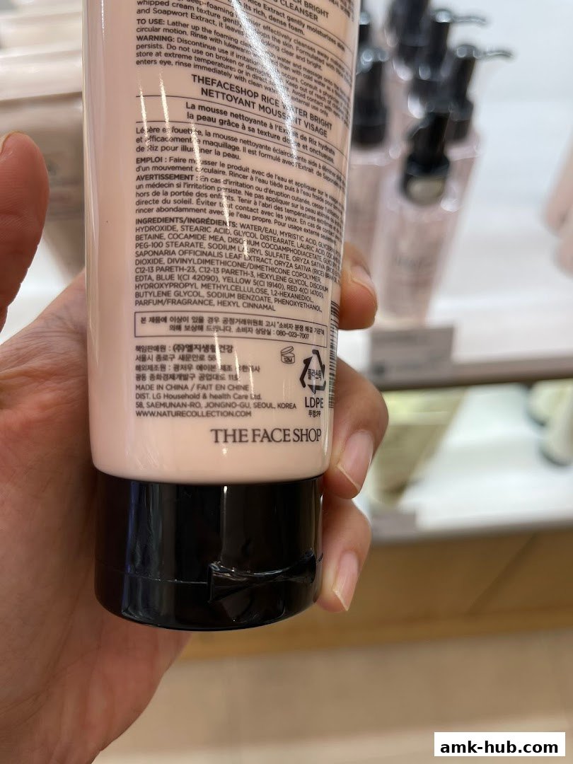 Close-up of a hand holding a bottle of THEFACESHOP Rice Water Bright Cleanser.