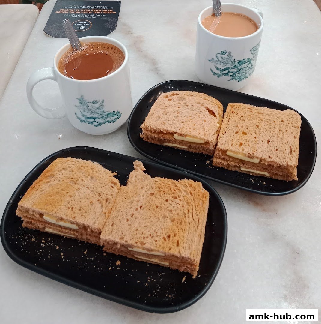 Two cups of coffee and toast with butter served on black plates.