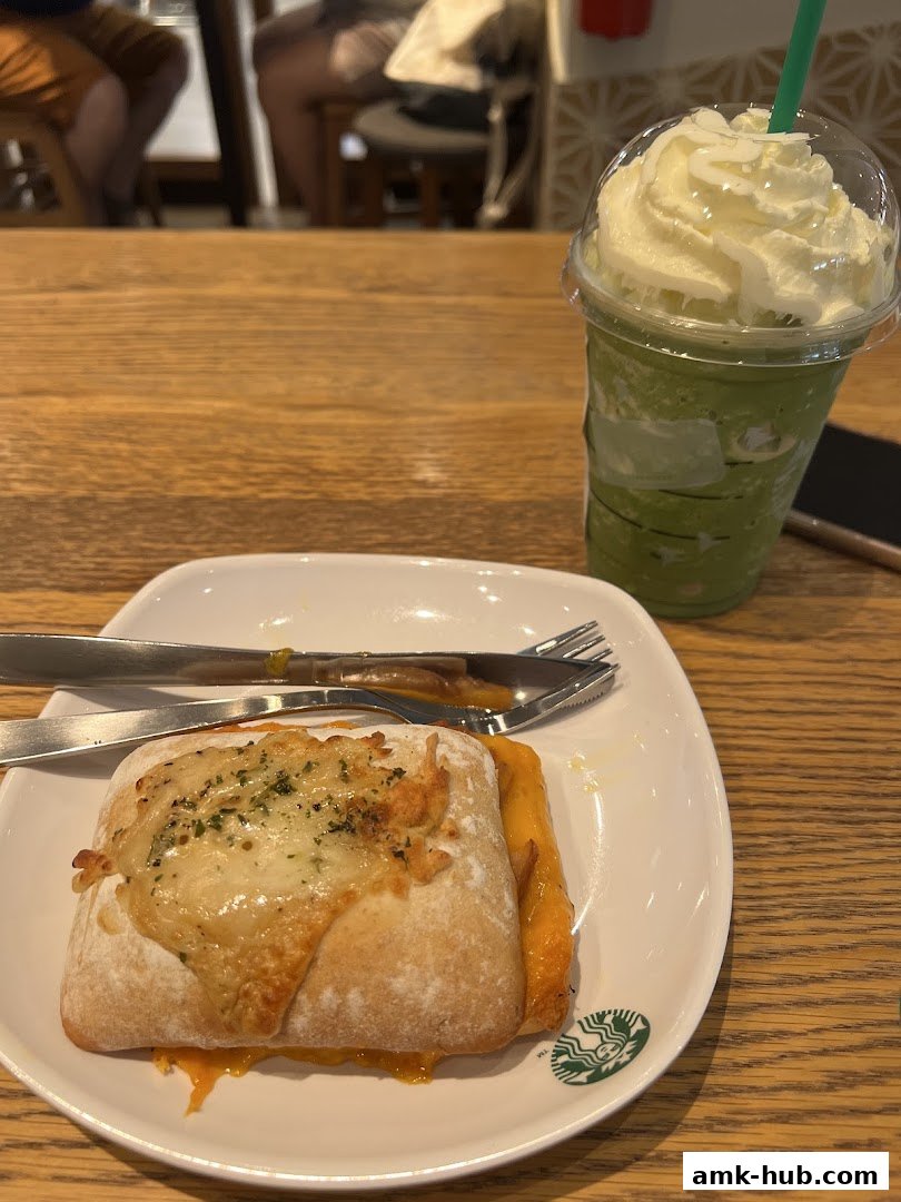 A delicious pastry and a green Frappuccino with whipped cream on a wooden table.