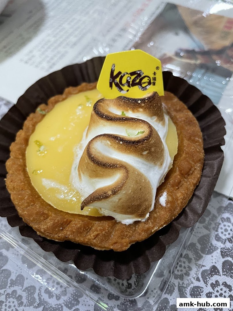 A close-up of a lemon meringue tart with a Kazo logo.