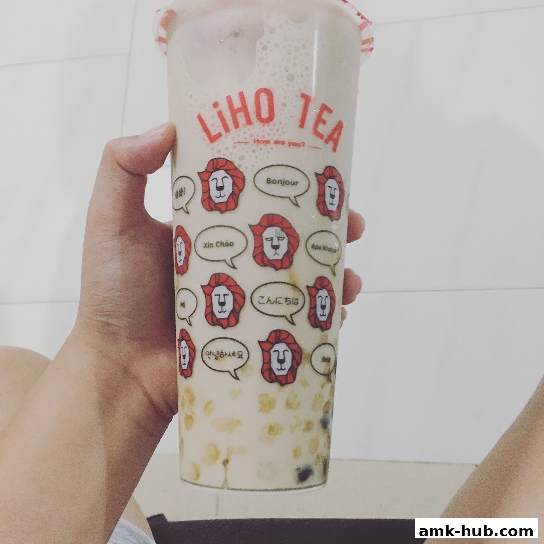A hand holds a LiHO TEA cup with various greetings in different languages.
