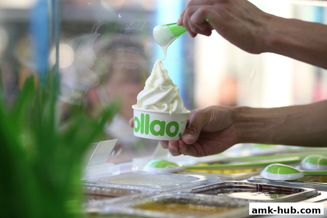 A hand is adding frozen yogurt to a cup with the llaollao logo.