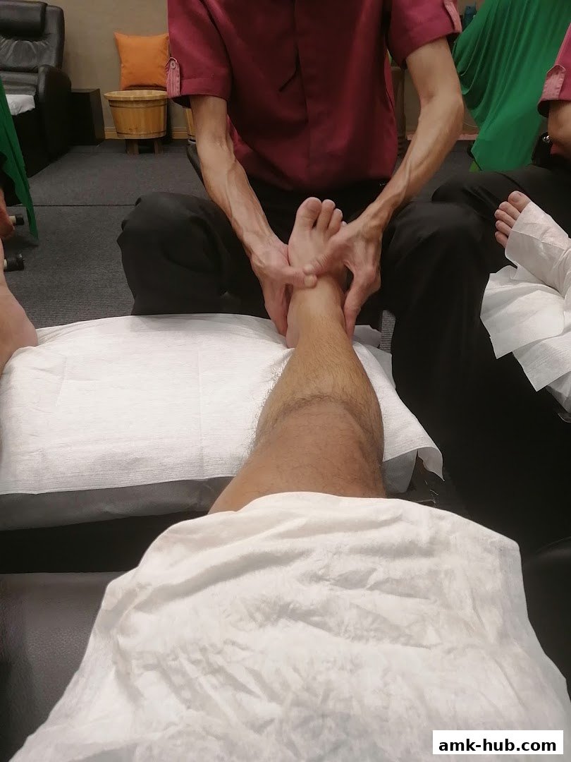 A person receiving a foot massage at a reflexology center.