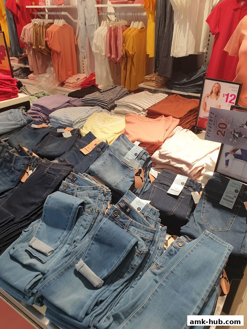 Neatly folded jeans and t-shirts displayed on shelves and tables in a retail store.
