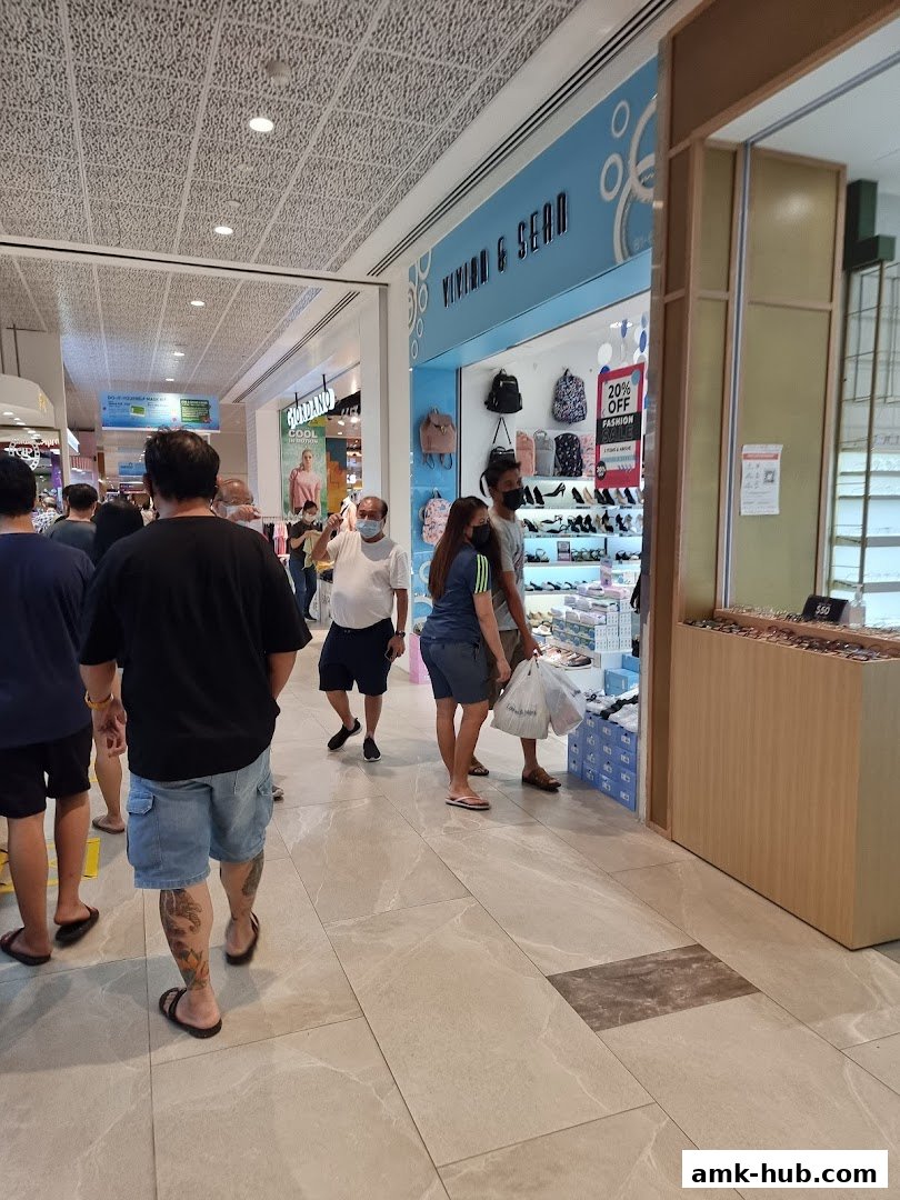 Shoppers walk past a Giordano store and a fashion store with bags and shoes on display.