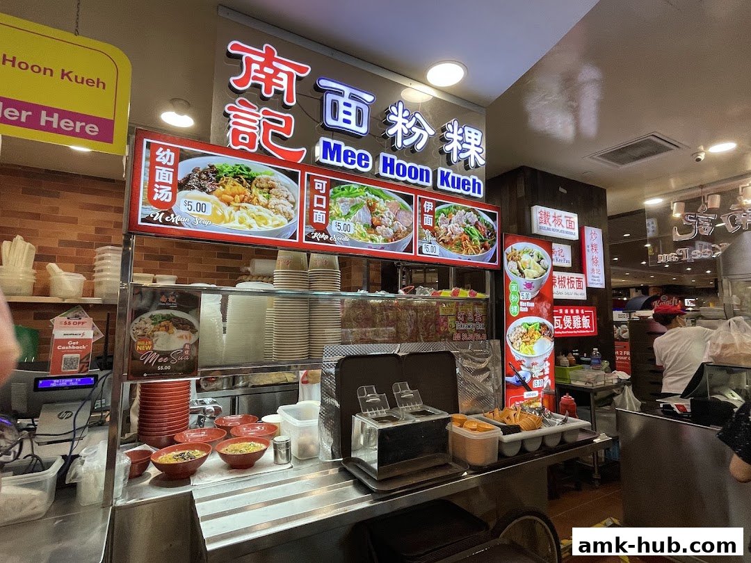 A food stall displaying various noodle dishes and rice dishes with prices.