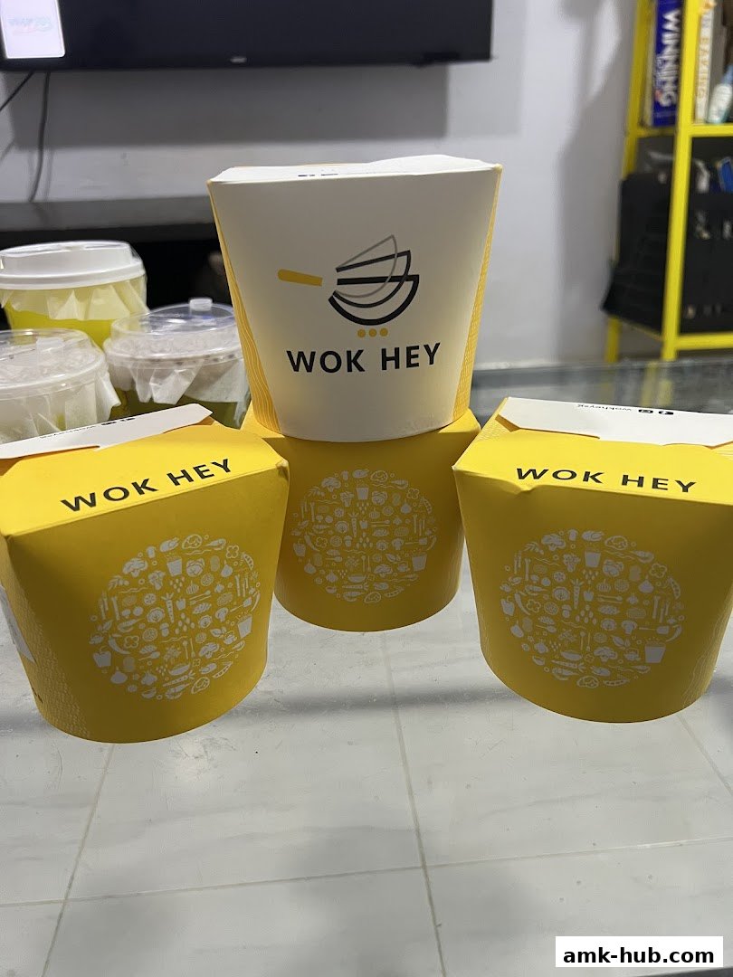 Several Wok Hey takeaway food containers are displayed, featuring the brand's logo and colorful illustrations.