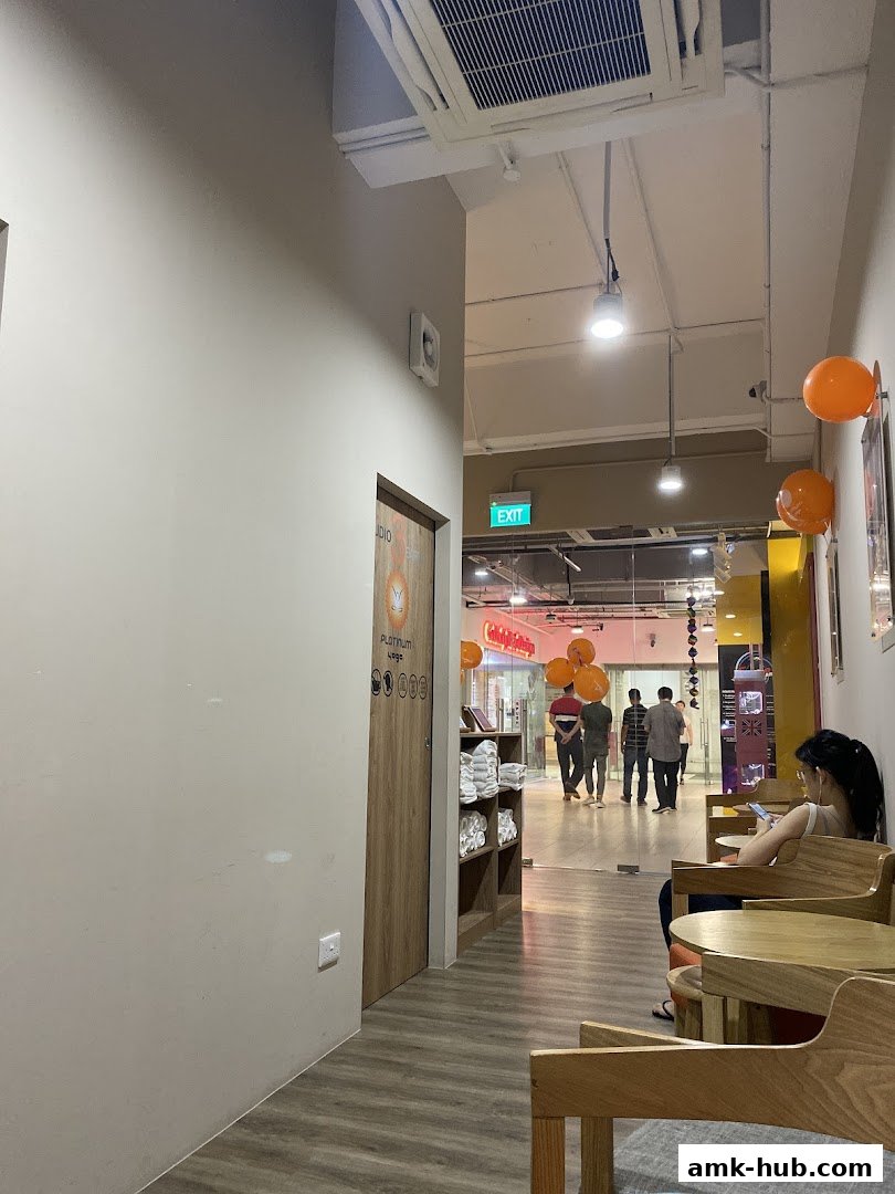 Interior view of a yoga studio hallway with a door and seating area.