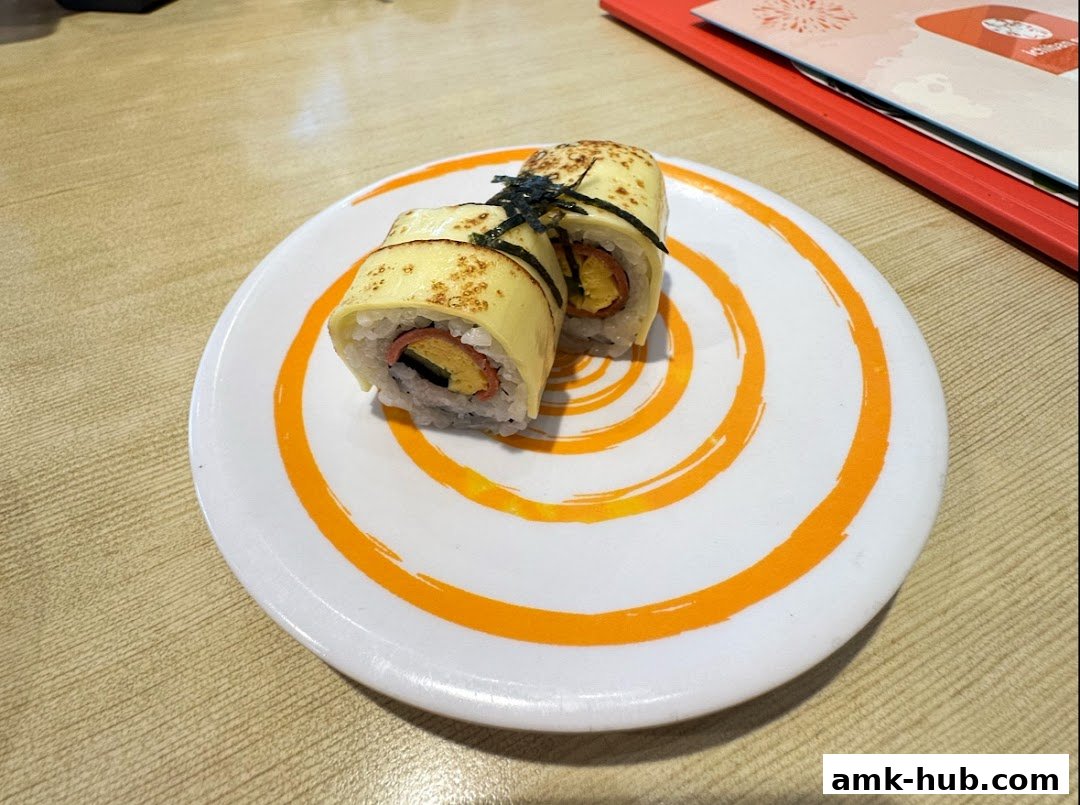 A plate of sushi rolls with a cheese topping and seaweed garnish on a table.