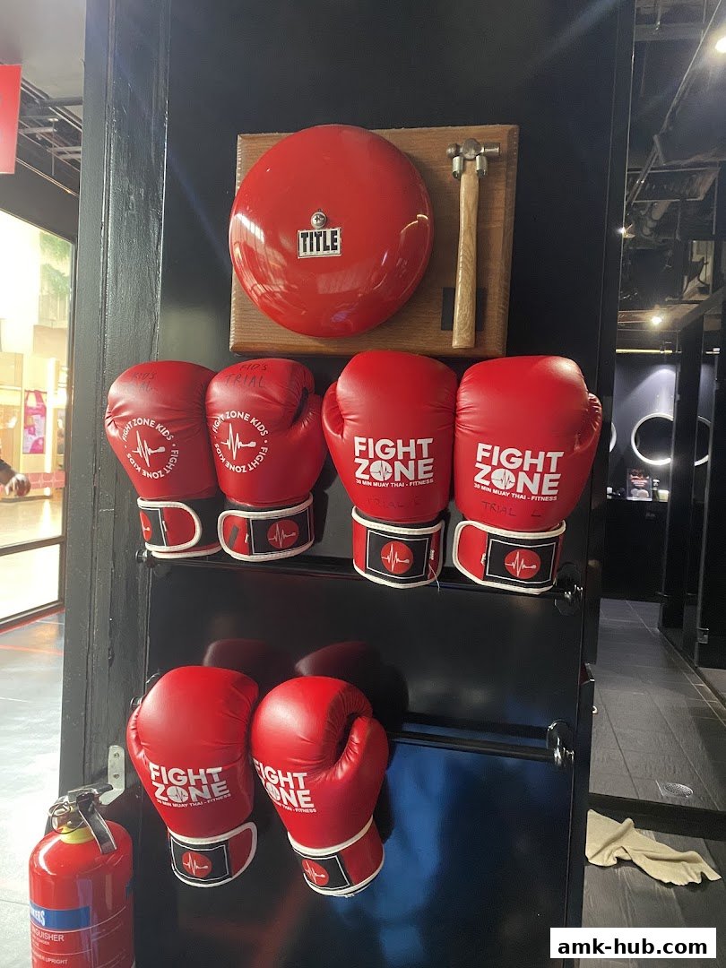 Red boxing gloves, a bell, and a hammer are displayed on a black wall.