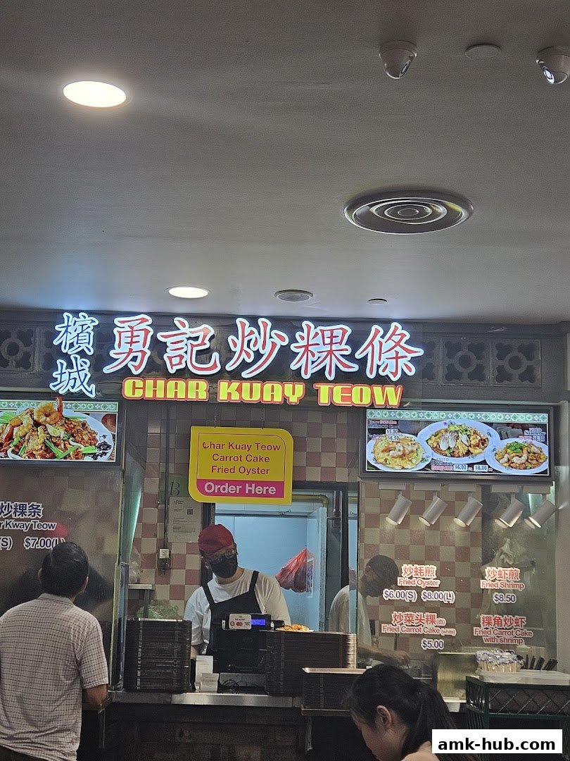 A food stall with a sign for Char Kuay Teow and images of dishes.