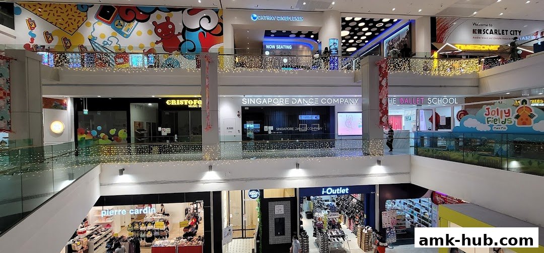 A multi-level shopping mall interior with various shops and escalators, decorated with festive lights.