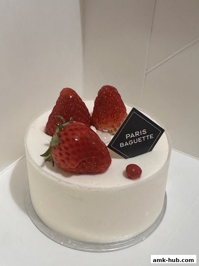 A delicious white cake topped with fresh strawberries and a Paris Baguette logo.
