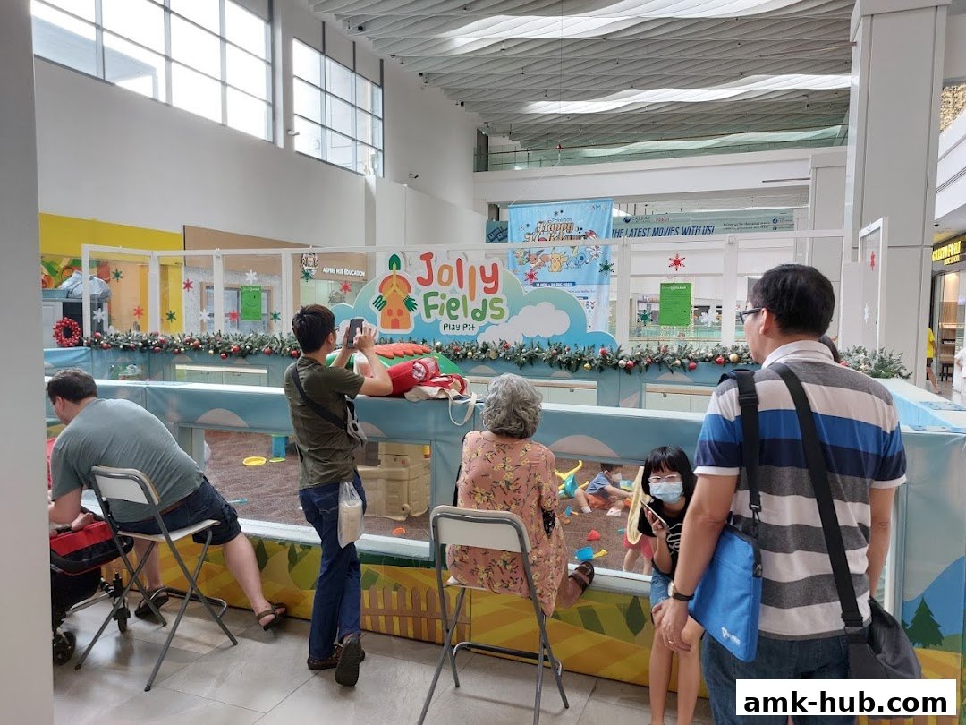 People watching children play in a colorful indoor play area decorated for the holidays.