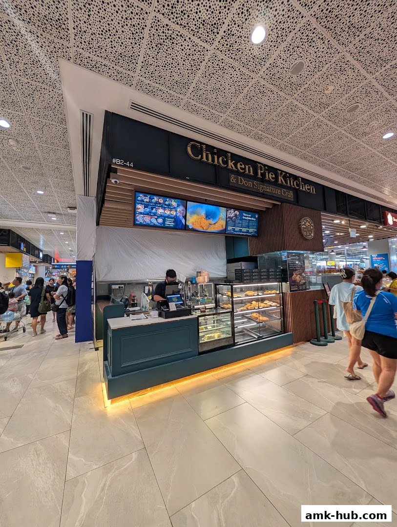 A Chicken Pie Kitchen shop with pies displayed in a refrigerated case and a staff member at the counter.