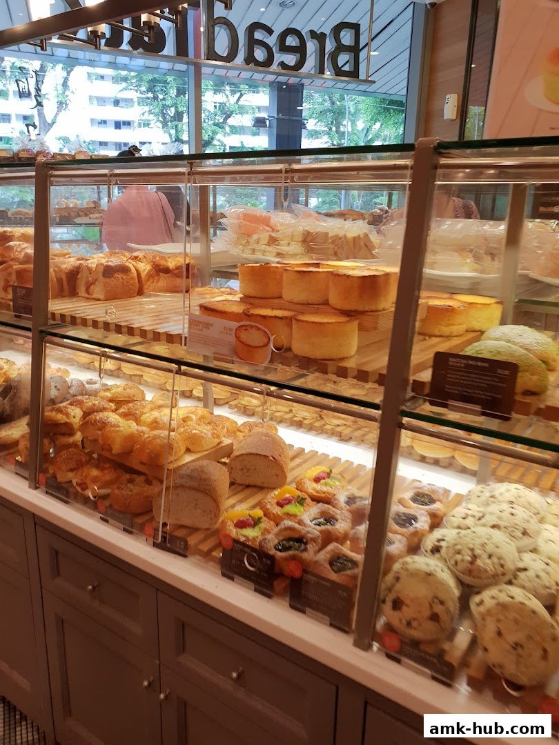 A display case filled with various freshly baked breads, pastries, and cakes.
