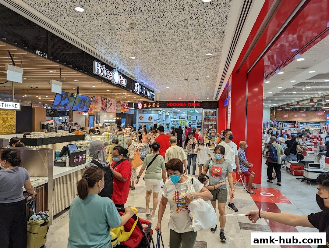 People shopping in a busy Japanese market with various food stalls and products.