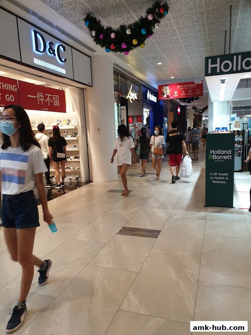 People walk past a D&C shoe store and a Holland & Barrett store in a mall.