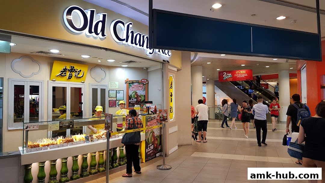 Old Chang Kee shop front with staff serving customers and displaying various fried snacks.