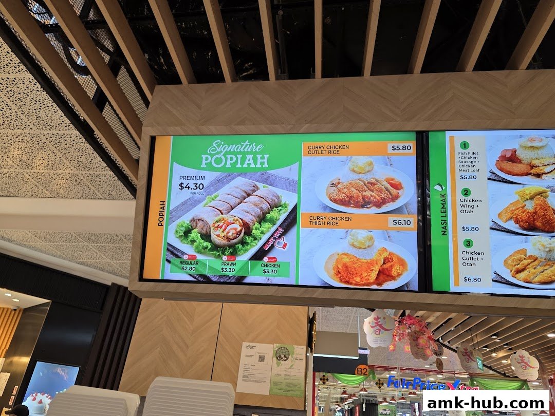 A digital menu board displaying various dishes including Popiah, Curry Chicken Rice, and Nasi Lemak.