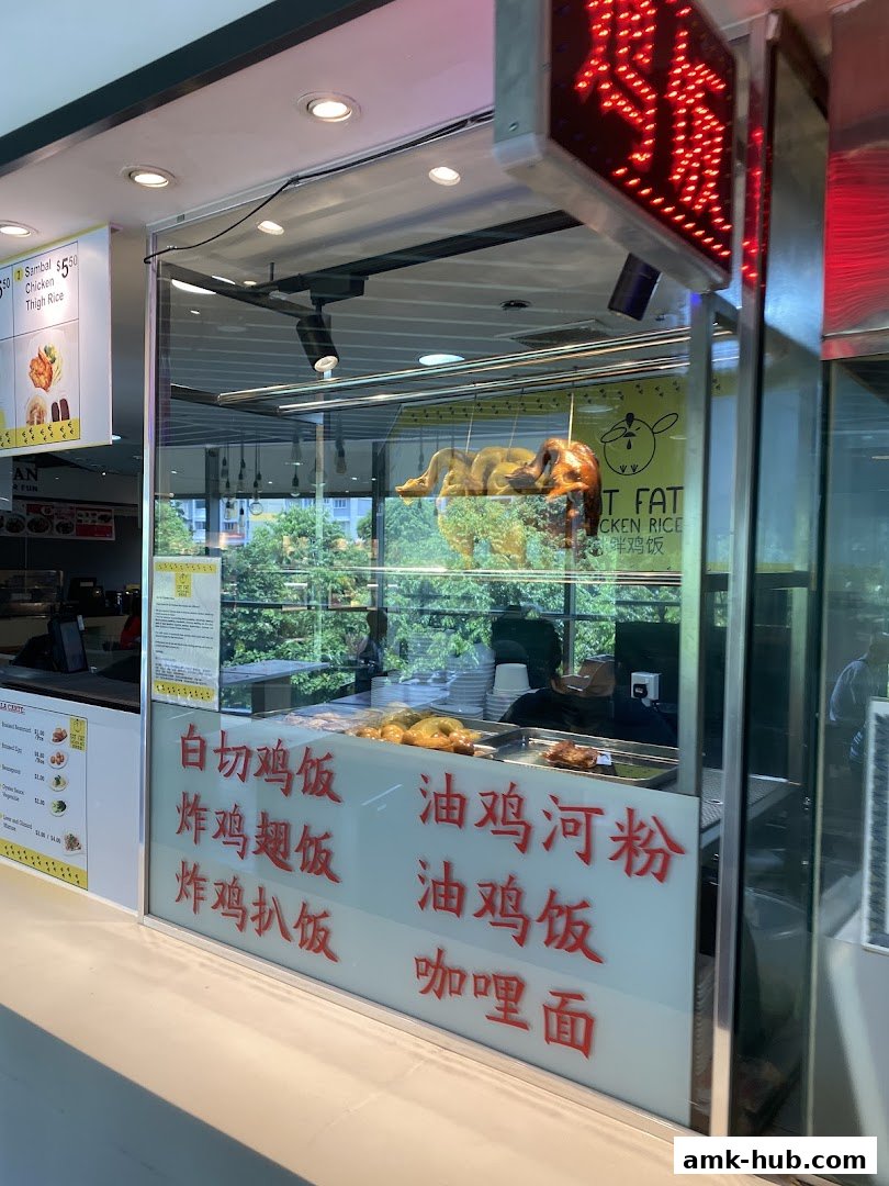 A food stall with roasted chickens hanging and menu items displayed on the glass.