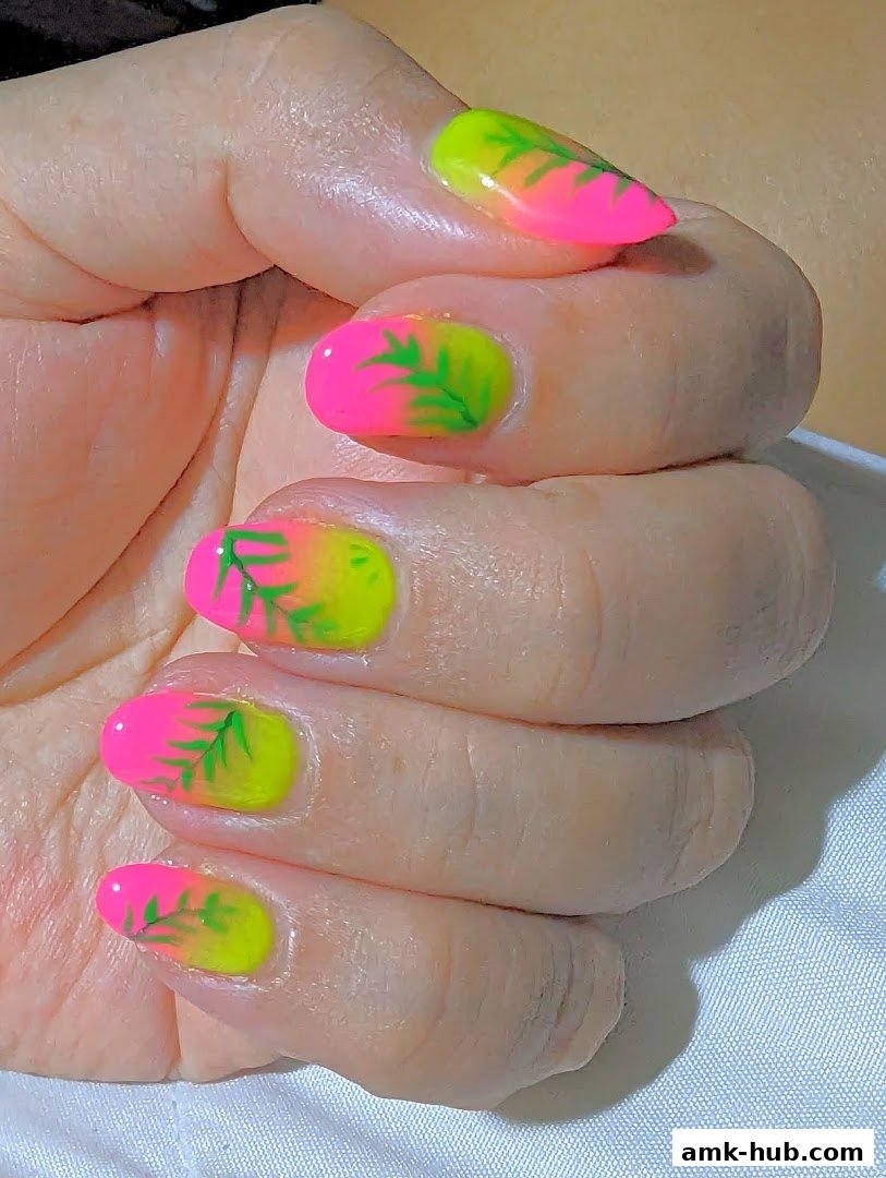 Close-up of a hand with vibrant neon pink and yellow gradient nails featuring green leaf designs.
