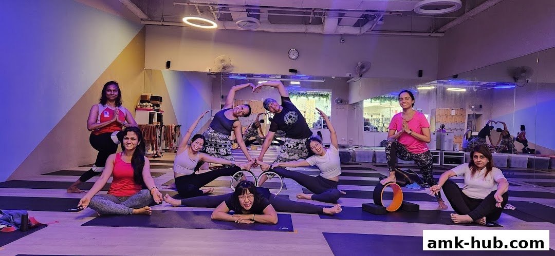 A group of people practicing yoga poses in a studio with mirrors and yoga wheels.