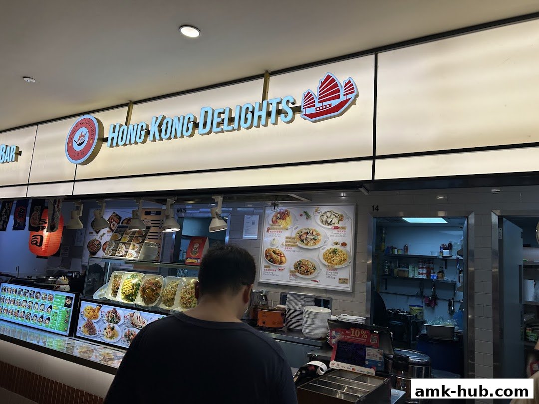 A customer stands in front of the Hong Kong Delights MiniwokFoodfare counter with menu displays.