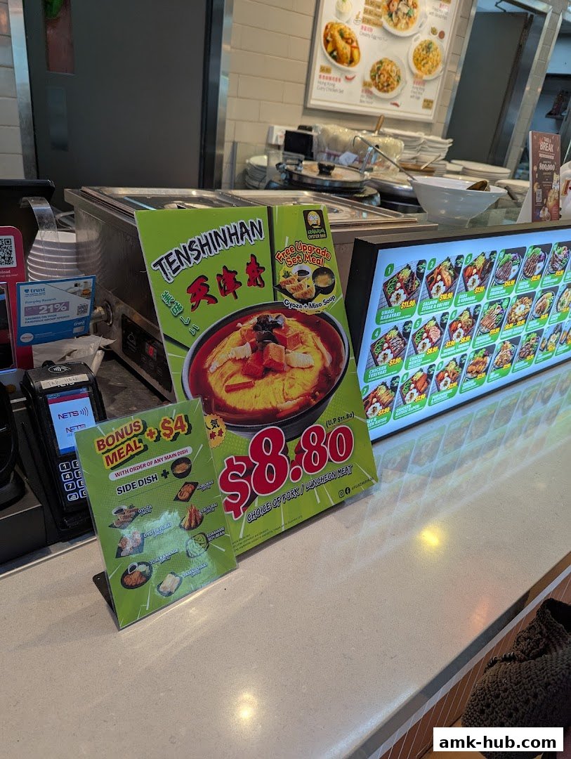 A counter display with food promotions and a digital menu board at Kopitiam.