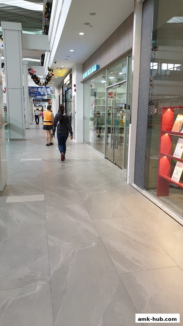 A view of a shopping mall corridor with several shop entrances, including one for Income Insurance.