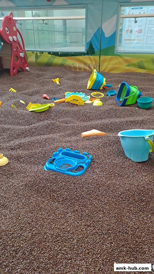 A sandpit filled with colorful toys for children's play.
