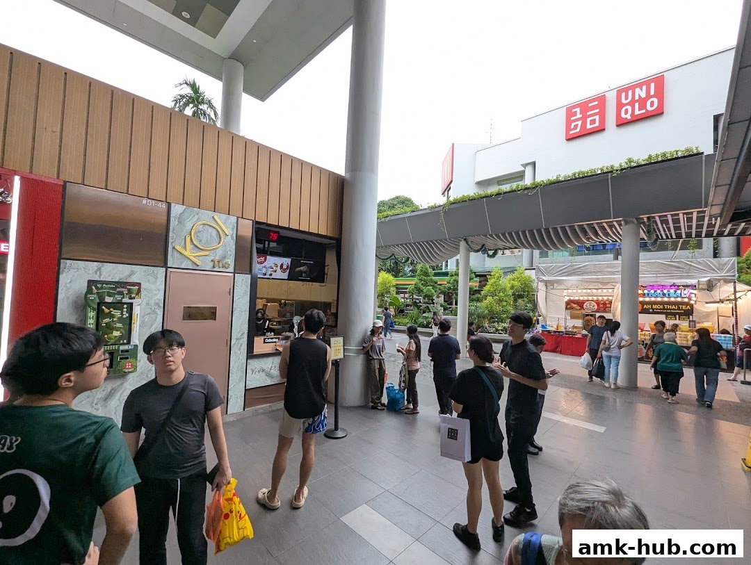 People queuing outside KOI Thé and Uniqlo stores in a mall.