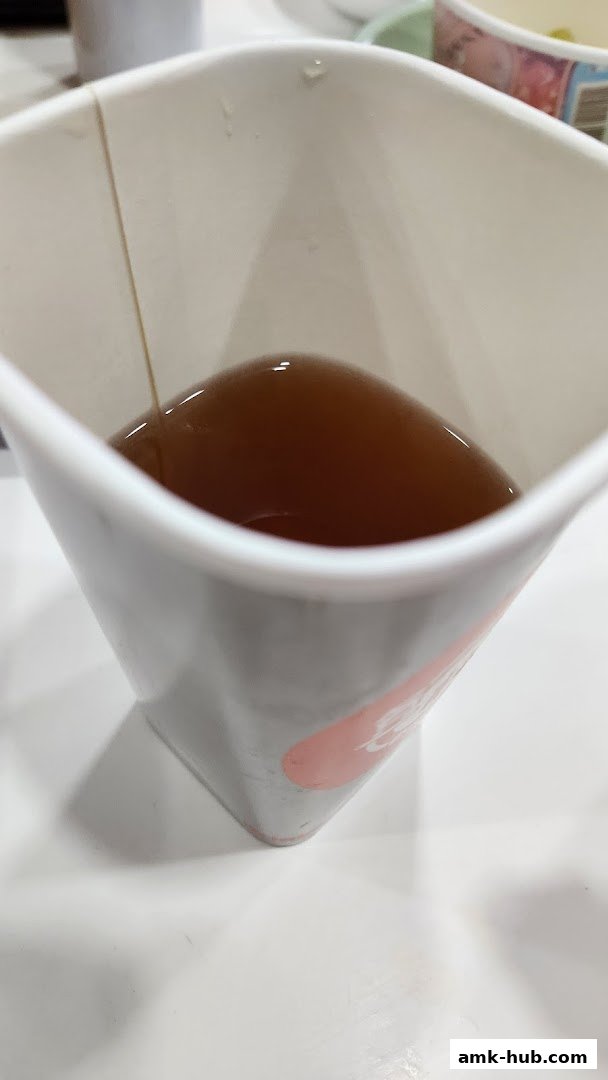 A close-up of a white cup filled with a dark beverage, likely tea.