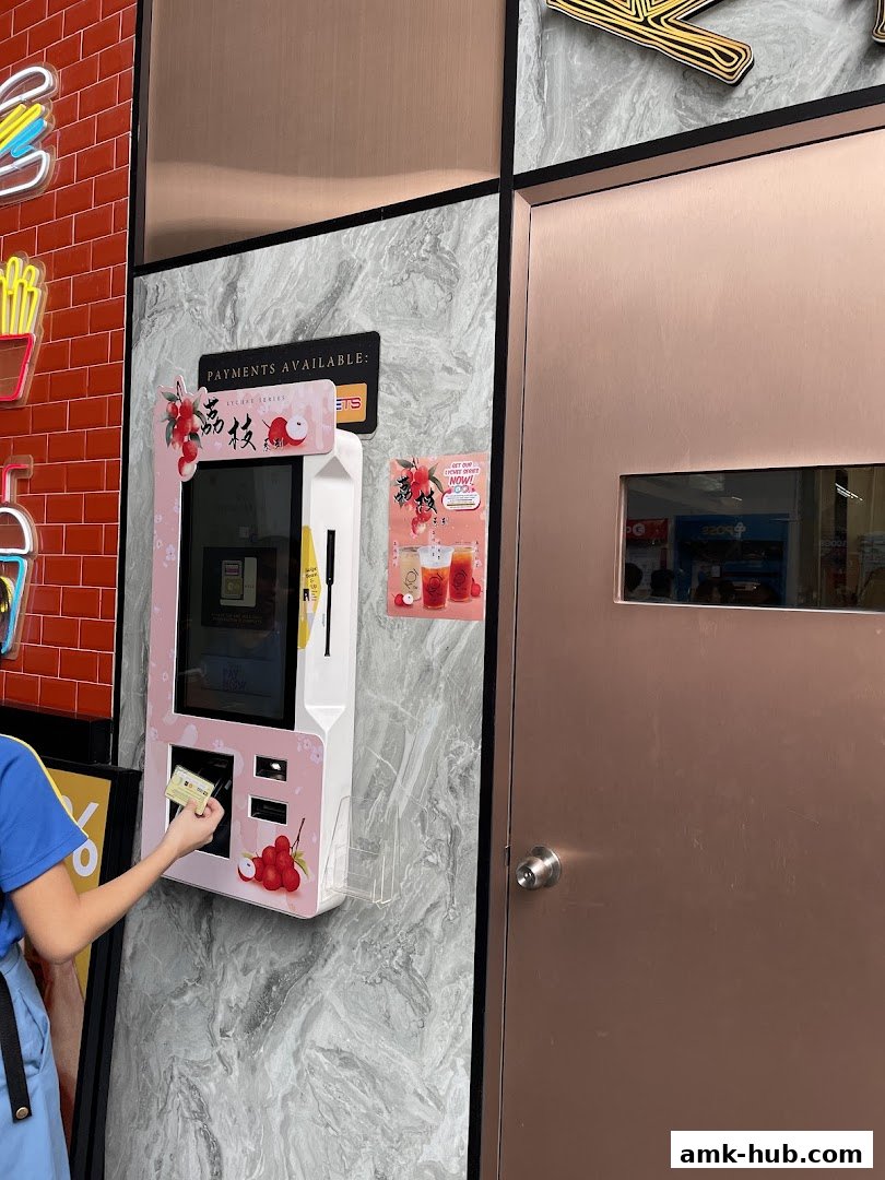 A person uses a self-ordering kiosk at KOI Thé, featuring lychee-themed promotions.