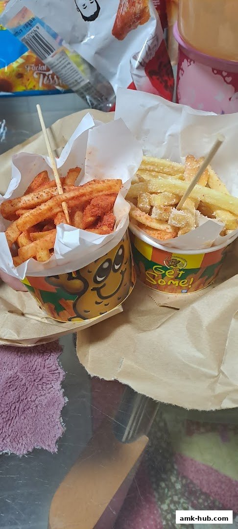 Two cups of flavored french fries, one with red seasoning and the other with white seasoning.