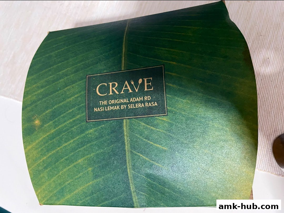 A package wrapped in green paper with a leaf pattern, featuring the Crave Nasi Lemak logo.