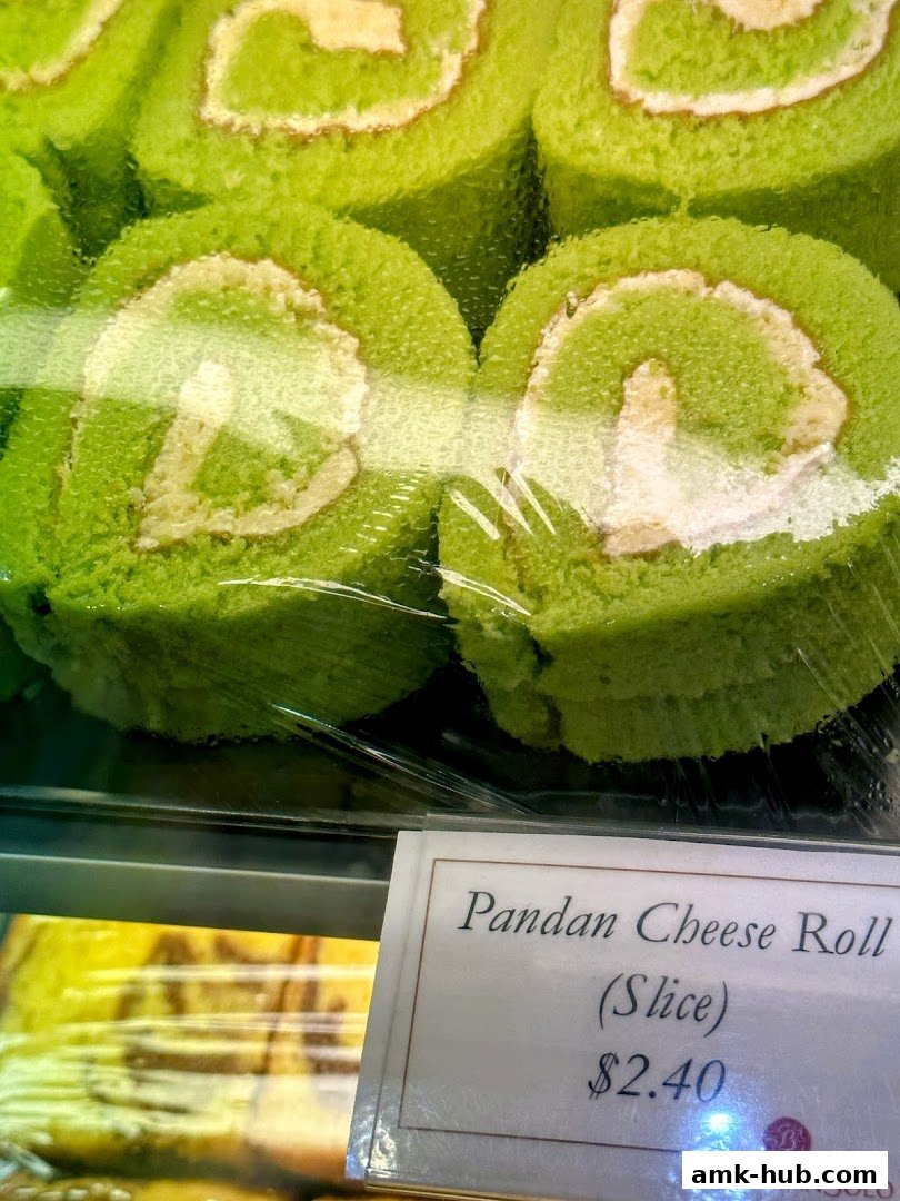 Close-up of bright green pandan cheese roll slices displayed in a bakery case.